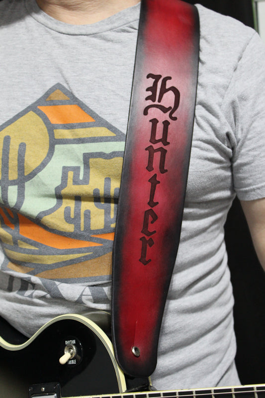 A man wearing a non-stitched red leather strap with black around the border and the word Hunter engraved on it.