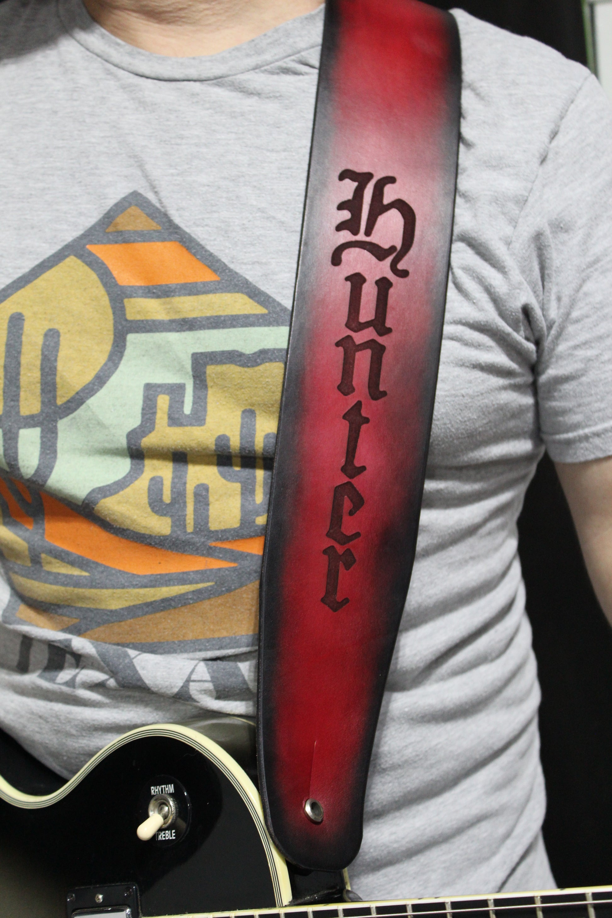 A man wearing a non-stitched red leather strap with black around the border and the word Hunter engraved on it. 